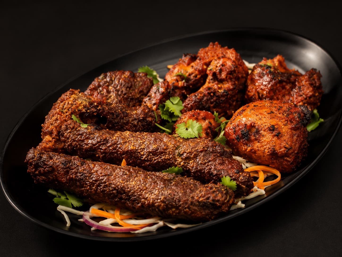 Seekh kebabs and chicken tikka on a black platter